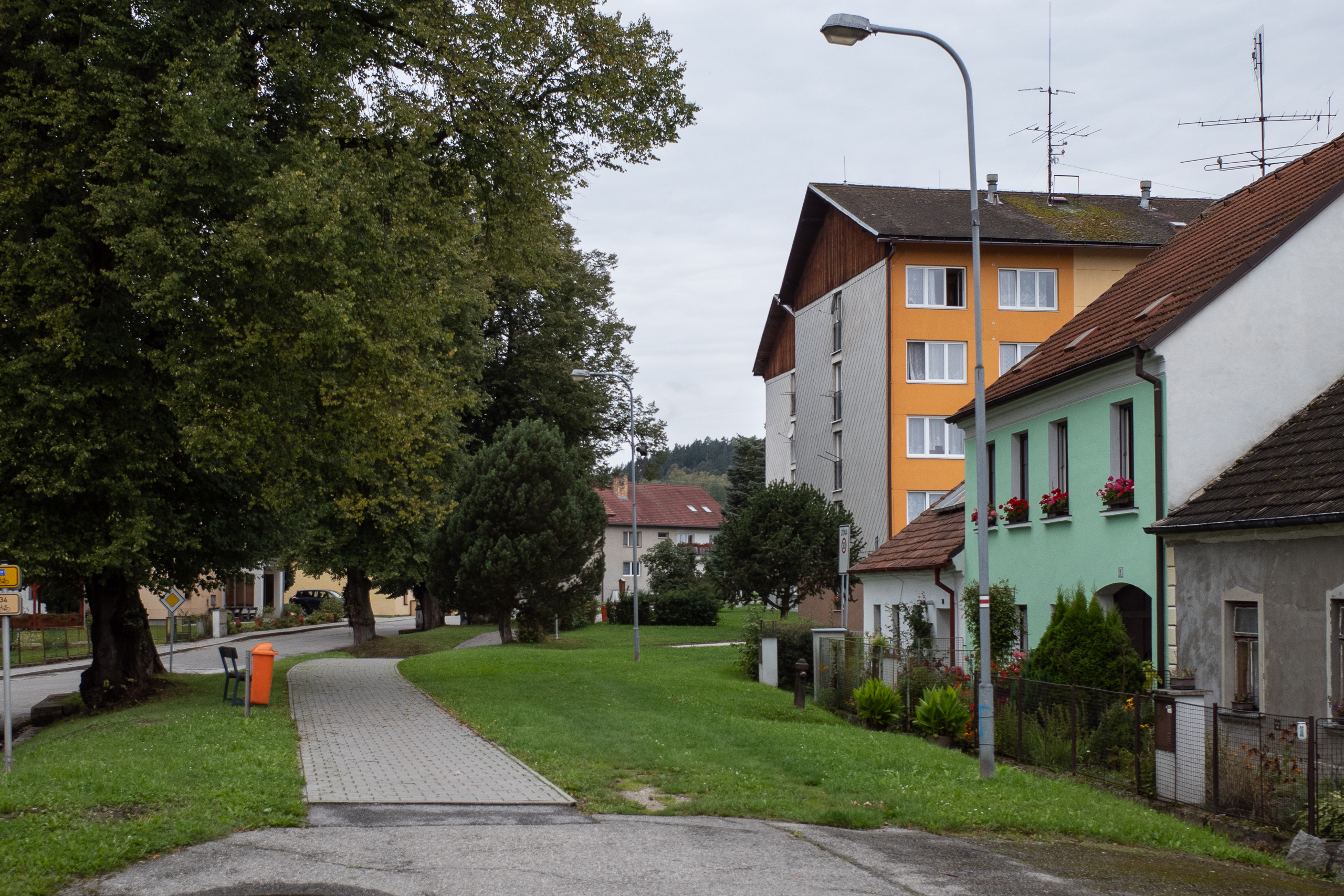 Ortsdurchfahrt: Plattenbau neben grün gestrichenem Altbau mit Geranien